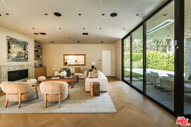 living room featuring light parquet floors, a wall of windows, and a premium fireplace