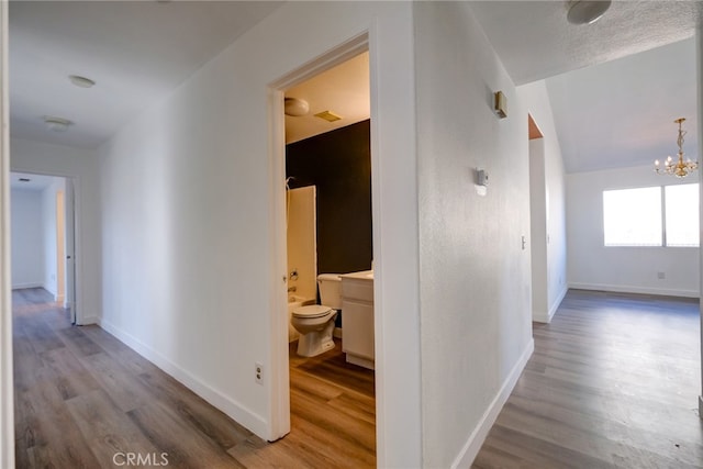 hallway featuring hardwood / wood-style flooring and an inviting chandelier