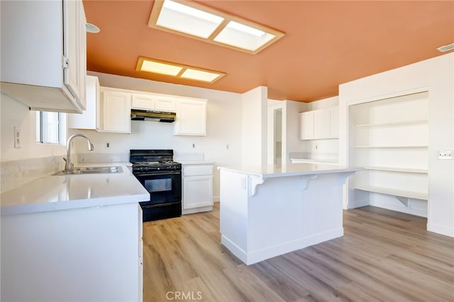 kitchen featuring gas stove, white cabinets, a kitchen island, light hardwood / wood-style flooring, and sink