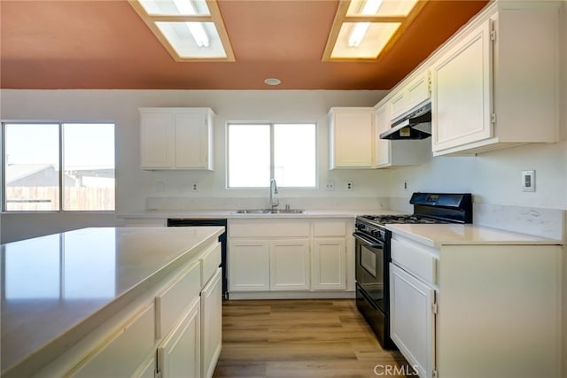 kitchen with sink, light hardwood / wood-style floors, white cabinetry, and black gas range oven