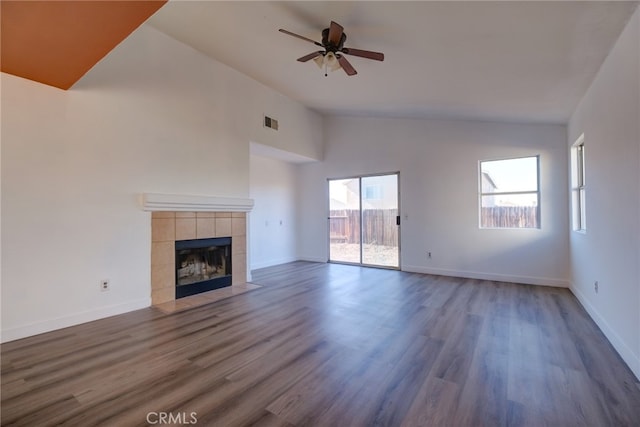 unfurnished living room featuring ceiling fan, high vaulted ceiling, a tile fireplace, and dark hardwood / wood-style flooring