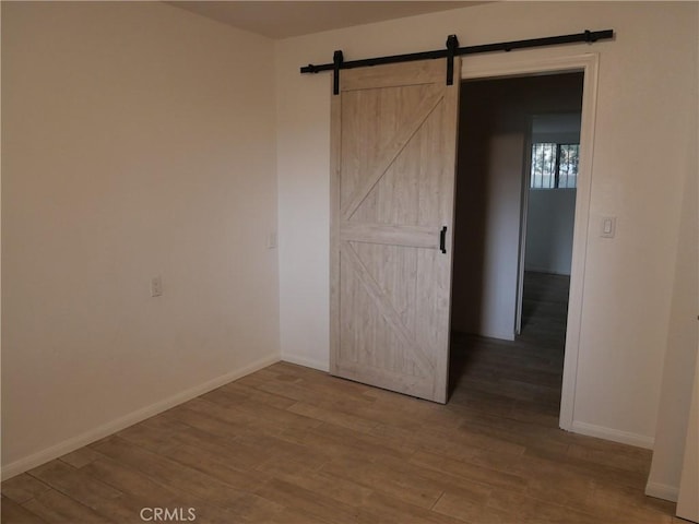 unfurnished room with a barn door and hardwood / wood-style floors