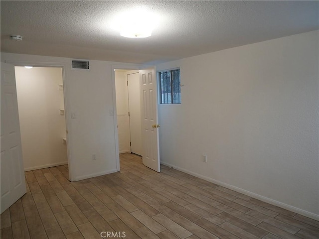 unfurnished bedroom featuring light hardwood / wood-style floors and a textured ceiling