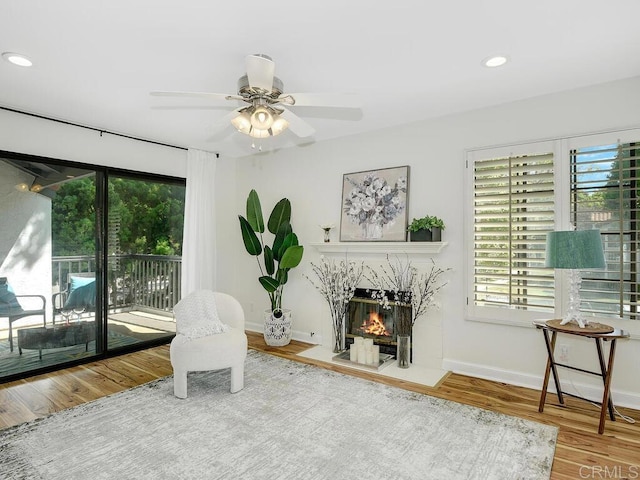 sitting room featuring a high end fireplace, hardwood / wood-style flooring, and ceiling fan