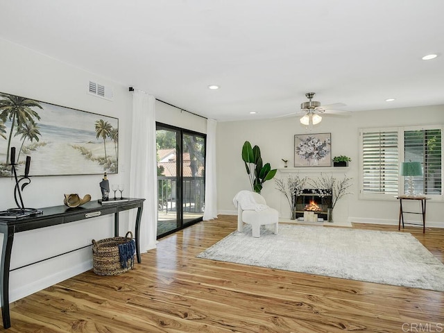 sitting room featuring ceiling fan, a high end fireplace, and hardwood / wood-style floors