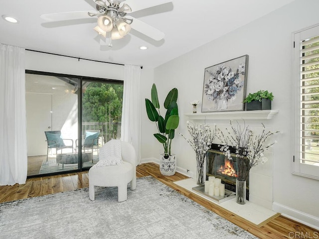 sitting room with a high end fireplace, hardwood / wood-style flooring, and ceiling fan