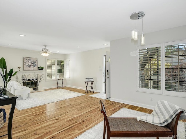 living room featuring ceiling fan, light wood-type flooring, and a fireplace