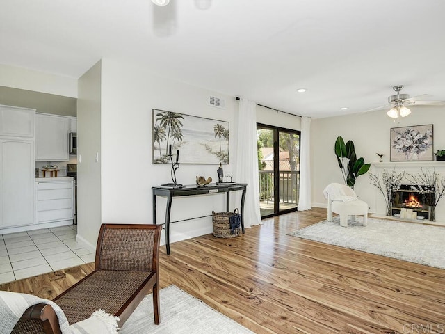 living room featuring light hardwood / wood-style floors, a fireplace, and ceiling fan