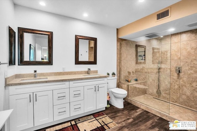 bathroom featuring toilet, hardwood / wood-style floors, vanity, and tiled shower