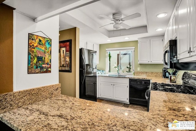 kitchen with white cabinets, sink, a tray ceiling, and black appliances