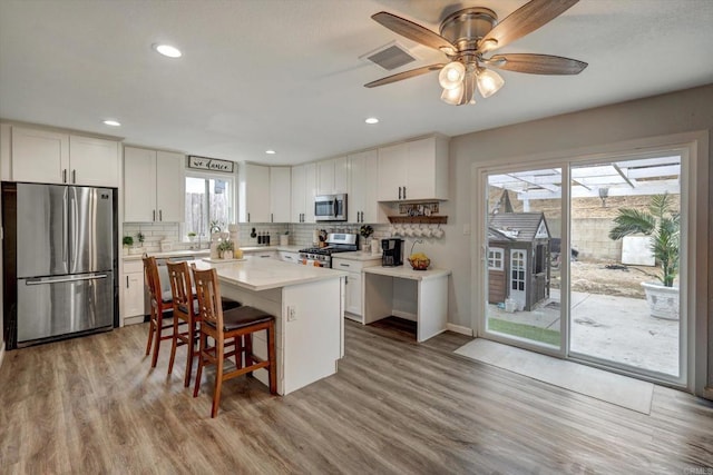 kitchen with white cabinetry, a center island, light hardwood / wood-style flooring, a breakfast bar, and appliances with stainless steel finishes