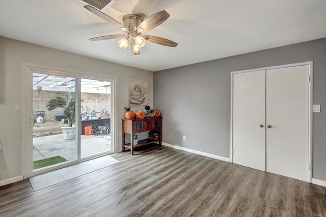 interior space featuring ceiling fan, wood-type flooring, access to exterior, and a closet