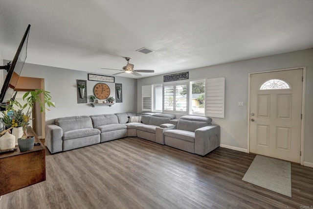 living room with dark wood-type flooring, plenty of natural light, and ceiling fan