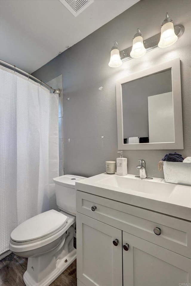 bathroom with walk in shower, wood-type flooring, toilet, and vanity