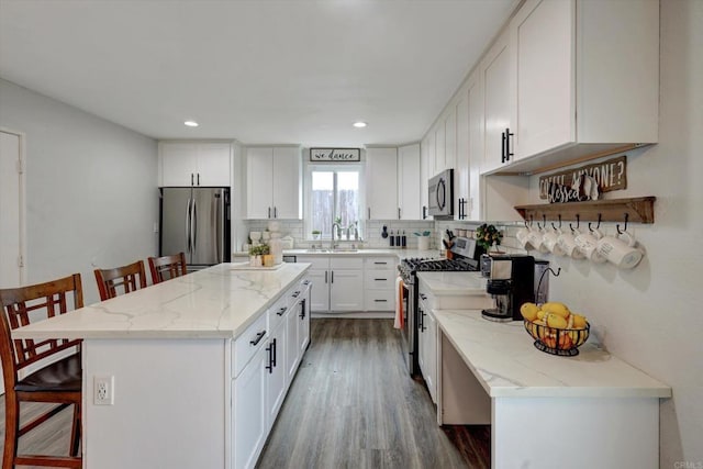 kitchen with stainless steel appliances, white cabinetry, a center island, and a breakfast bar