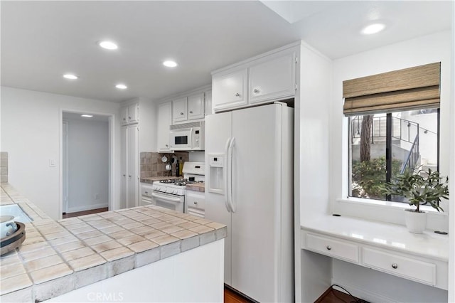 kitchen with hardwood / wood-style floors, white appliances, decorative backsplash, tile counters, and white cabinetry