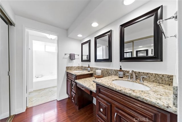 bathroom featuring hardwood / wood-style floors, vanity, and a bath