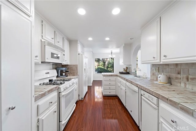 kitchen with white cabinetry, tile counters, sink, dark hardwood / wood-style floors, and white appliances