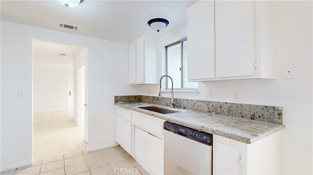 kitchen with light tile patterned floors, stainless steel dishwasher, white cabinets, and sink