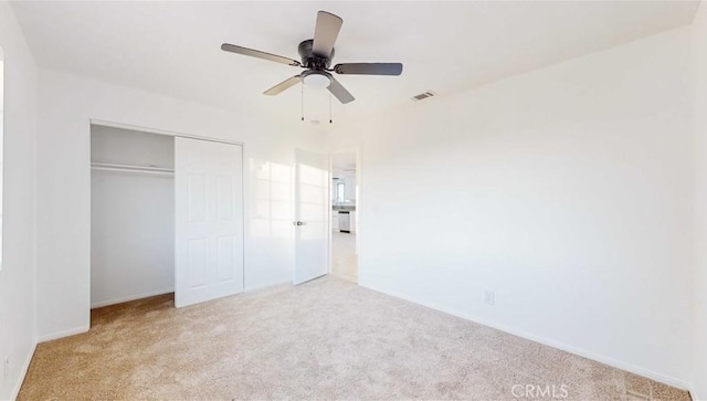 unfurnished bedroom featuring ceiling fan, light colored carpet, and a closet