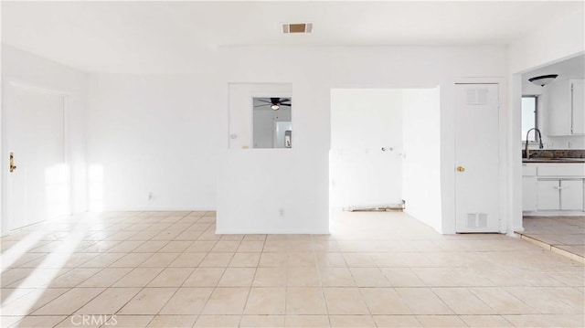 tiled spare room featuring ceiling fan and sink