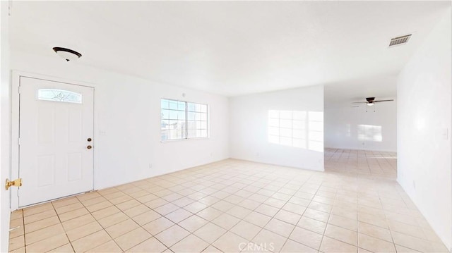 tiled spare room featuring ceiling fan and plenty of natural light