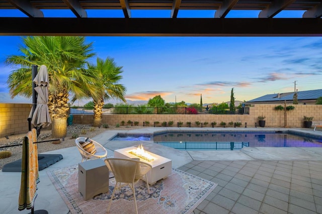 pool at dusk featuring a fire pit and a patio area