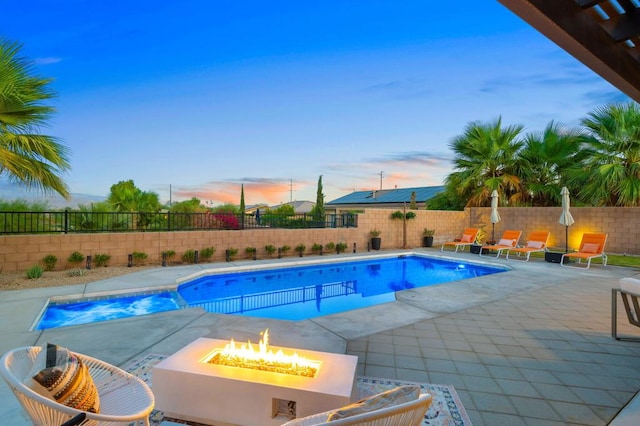 pool at dusk featuring a fire pit and a patio area