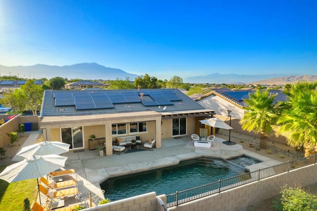 rear view of house with a mountain view, an outdoor hangout area, a fenced in pool, and a patio