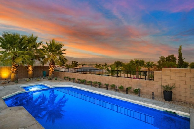 pool at dusk featuring an in ground hot tub