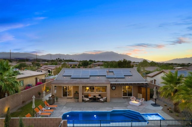 back house at dusk featuring a fenced in pool, a patio area, a mountain view, and an outdoor hangout area