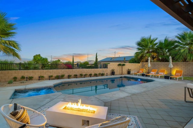 pool at dusk featuring a fire pit and a patio area