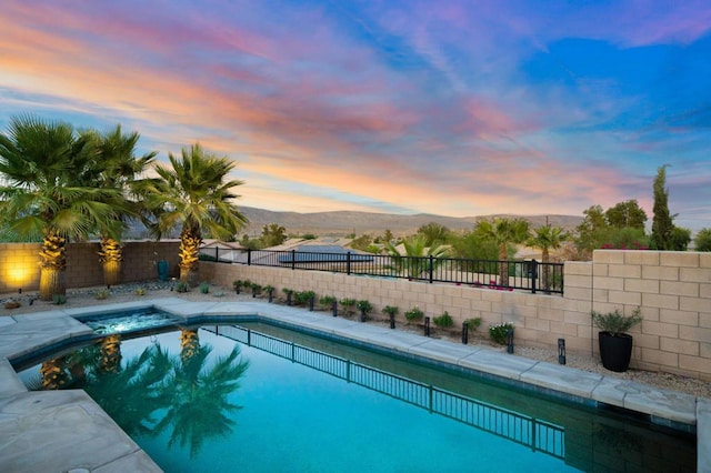 pool at dusk featuring a mountain view