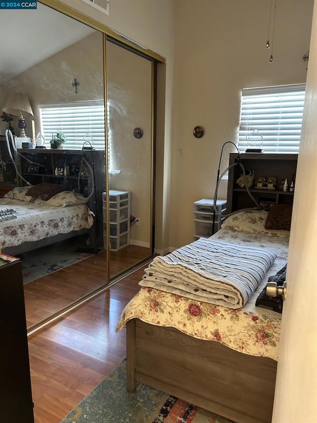 bedroom featuring hardwood / wood-style floors, a closet, and vaulted ceiling