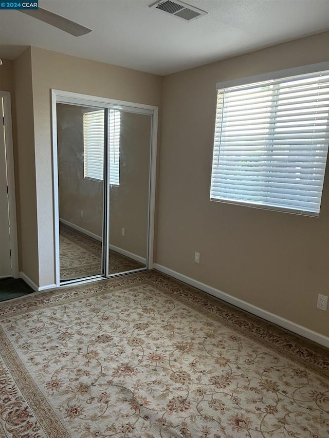 unfurnished bedroom featuring ceiling fan, a closet, and multiple windows