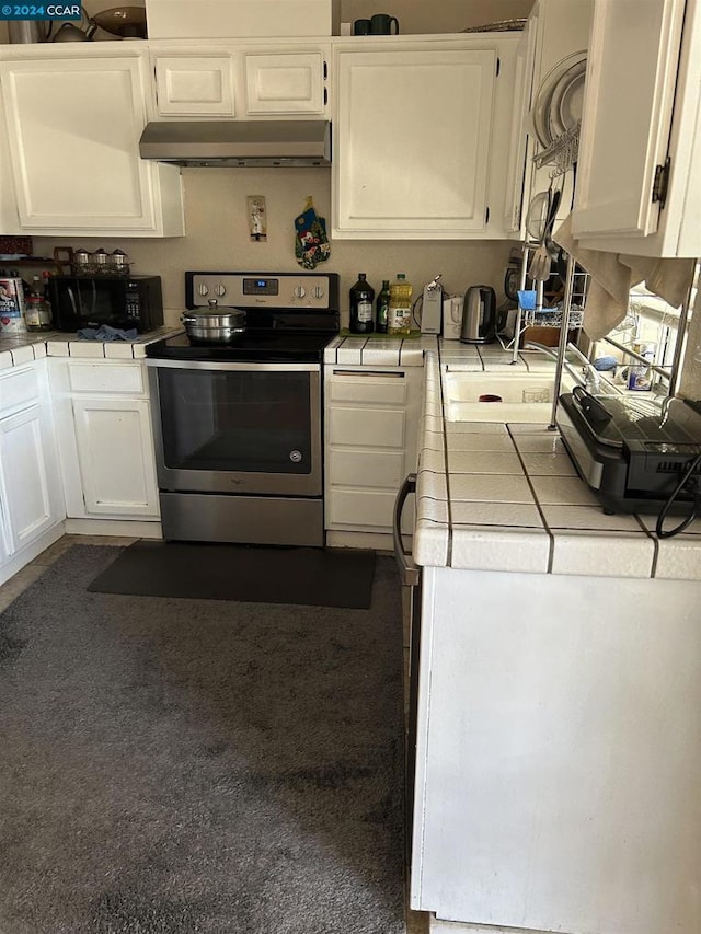 kitchen featuring stainless steel range with electric cooktop, tile countertops, and white cabinets