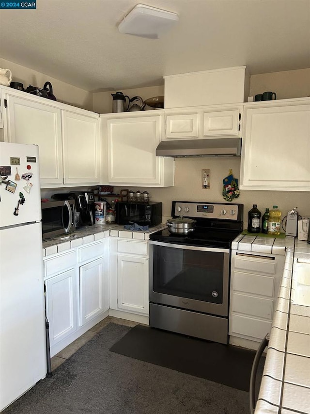 kitchen with white cabinets, appliances with stainless steel finishes, and tile countertops