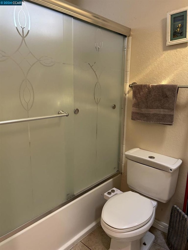 bathroom featuring shower / bath combination with glass door, toilet, and tile patterned flooring