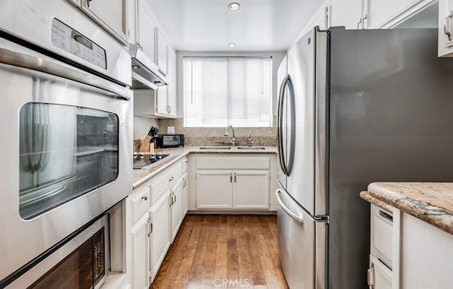 kitchen featuring decorative backsplash, stainless steel appliances, sink, light hardwood / wood-style floors, and white cabinetry