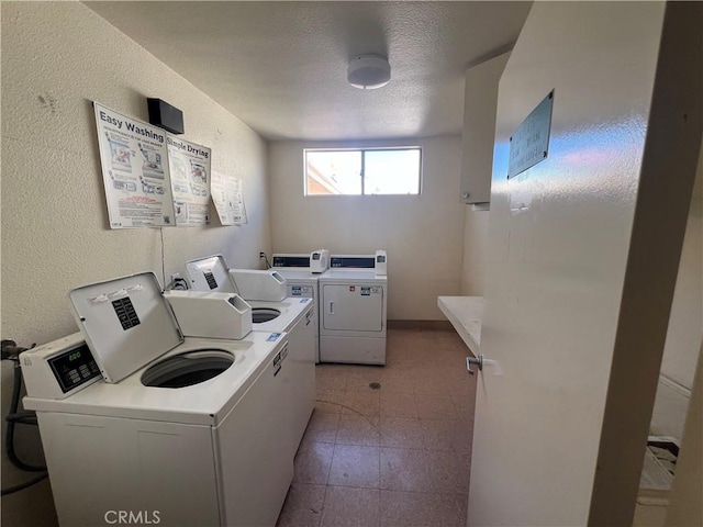 clothes washing area with a textured ceiling and washer and clothes dryer