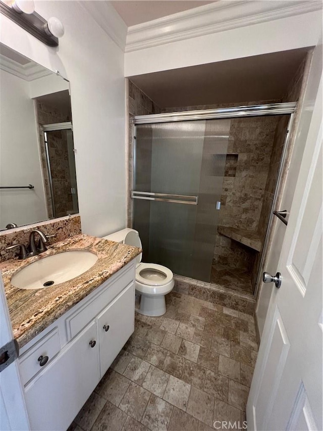 bathroom featuring walk in shower, crown molding, vanity, and toilet