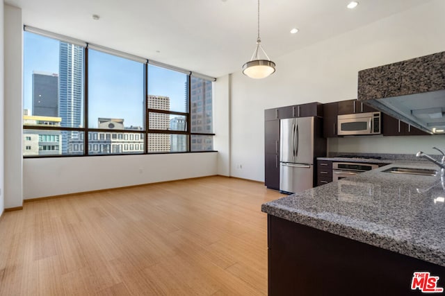 kitchen featuring sink, appliances with stainless steel finishes, hanging light fixtures, and light hardwood / wood-style floors