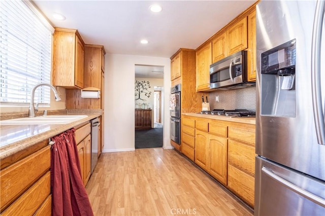 kitchen featuring backsplash, sink, light hardwood / wood-style floors, and appliances with stainless steel finishes