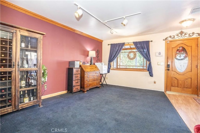 entrance foyer featuring dark carpet, crown molding, and rail lighting