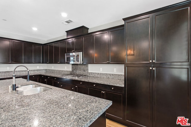 kitchen featuring light hardwood / wood-style flooring, stainless steel appliances, sink, light stone countertops, and dark brown cabinetry