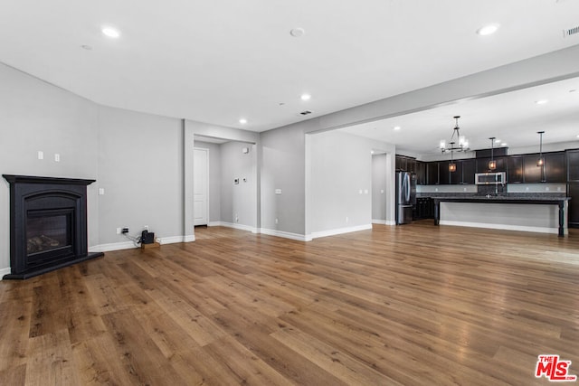 unfurnished living room featuring a chandelier and dark hardwood / wood-style flooring