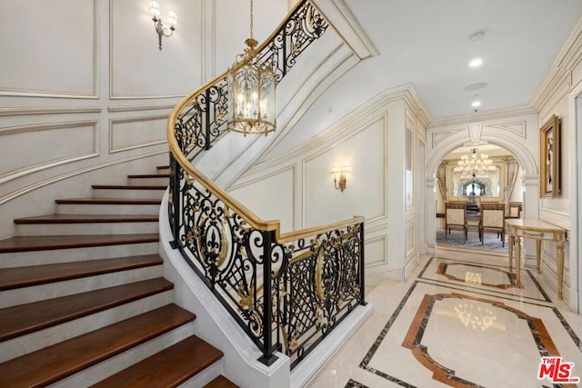 staircase featuring ornamental molding and a chandelier