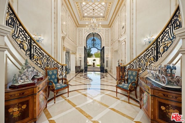 entrance foyer with a towering ceiling, ornamental molding, and a chandelier