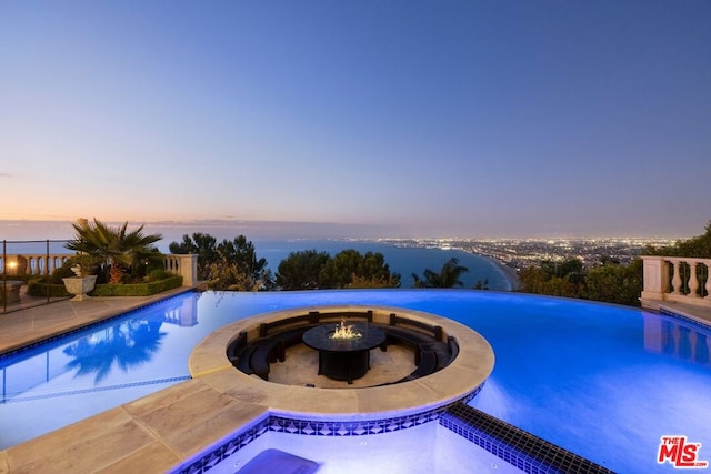 pool at dusk with a patio area and a fire pit