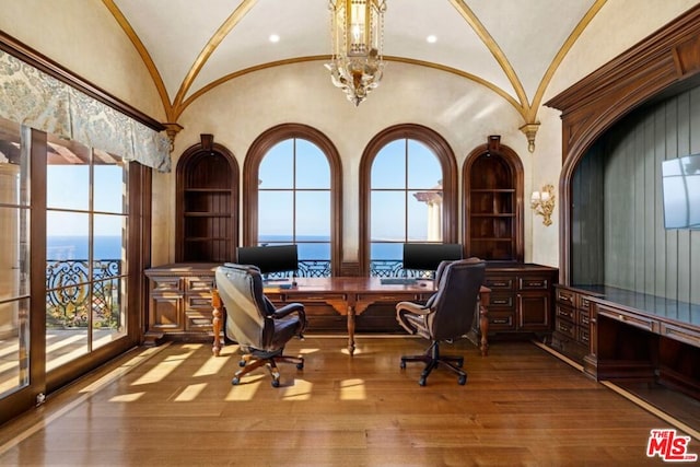 home office featuring built in desk, lofted ceiling, light hardwood / wood-style flooring, and a wealth of natural light